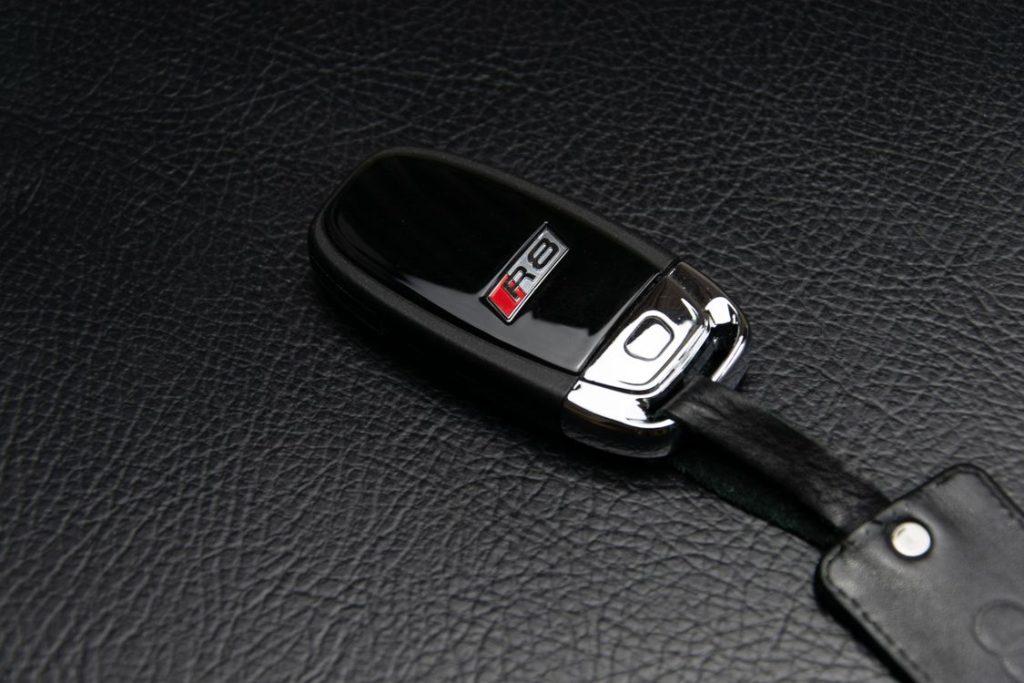 An original Audi R8 key fob resting on a leather surface.