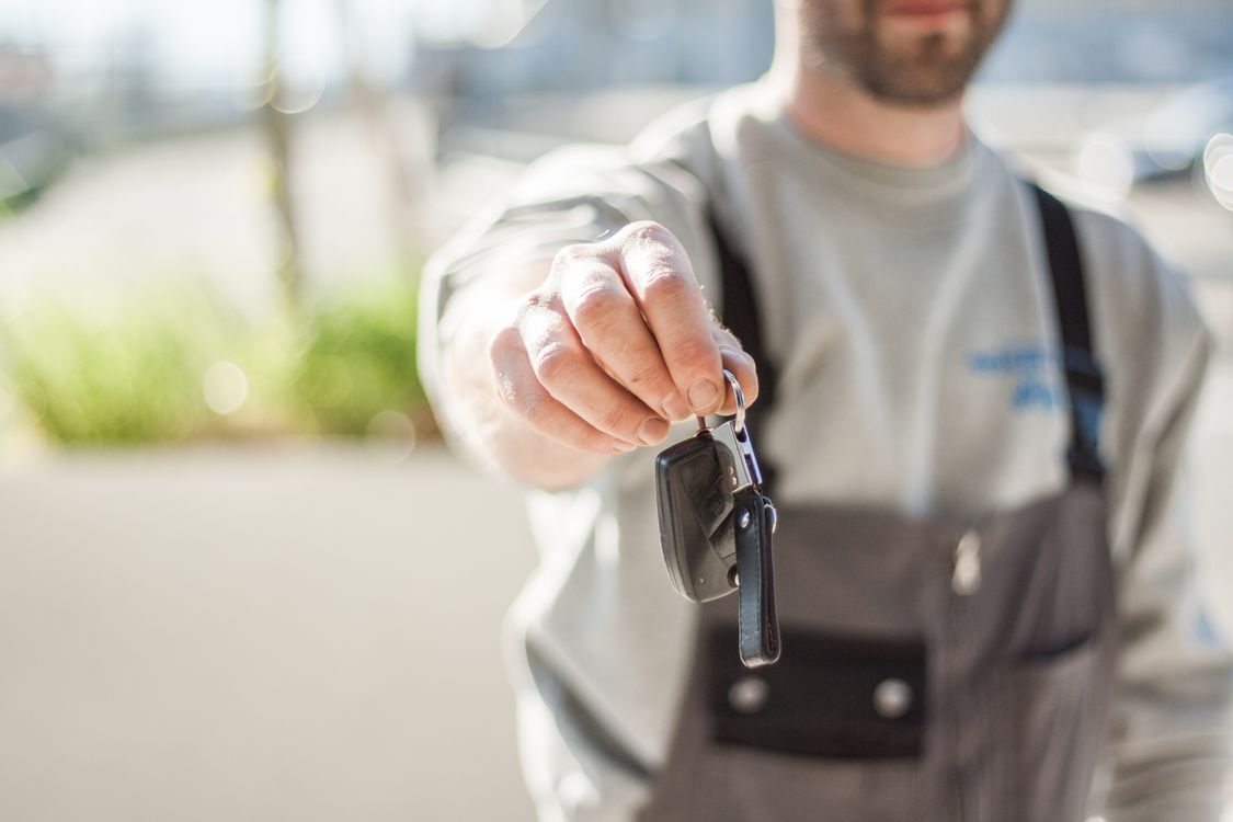 A person holding real vehicle keys outdoors.