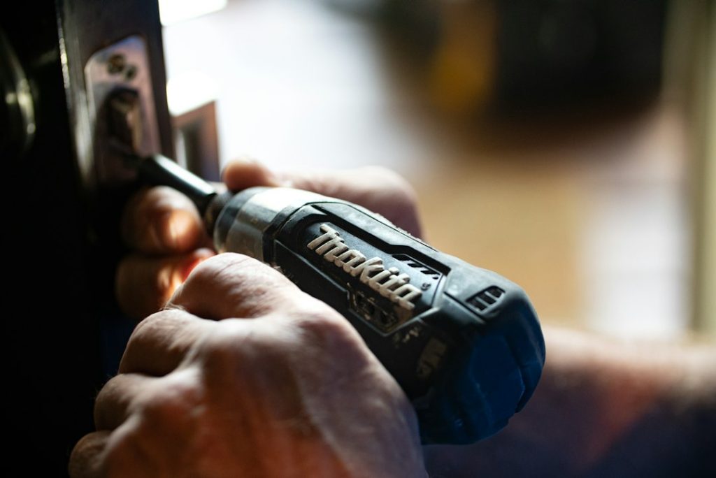 Hands using a drill while working on door hardware.