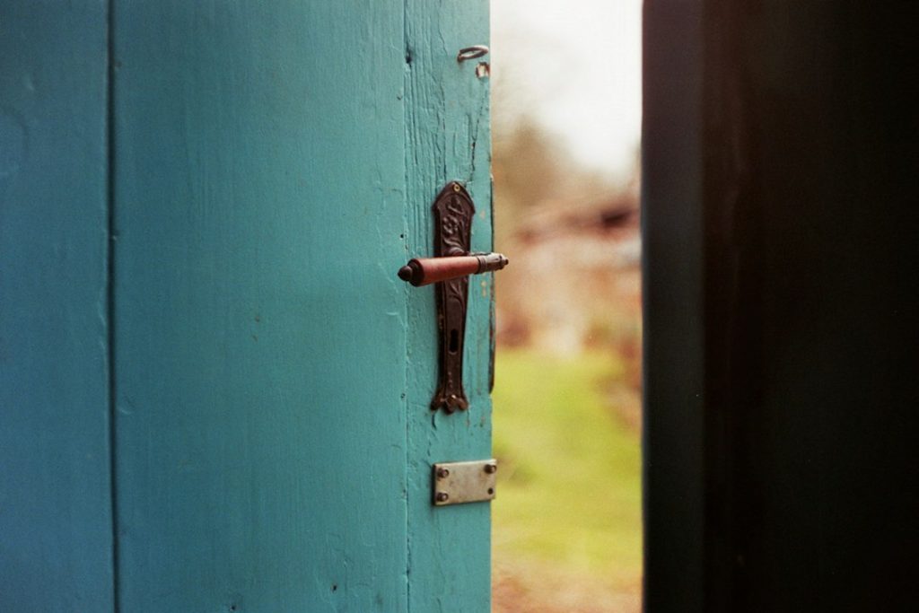 A weathered blue door with its original handle and lock.